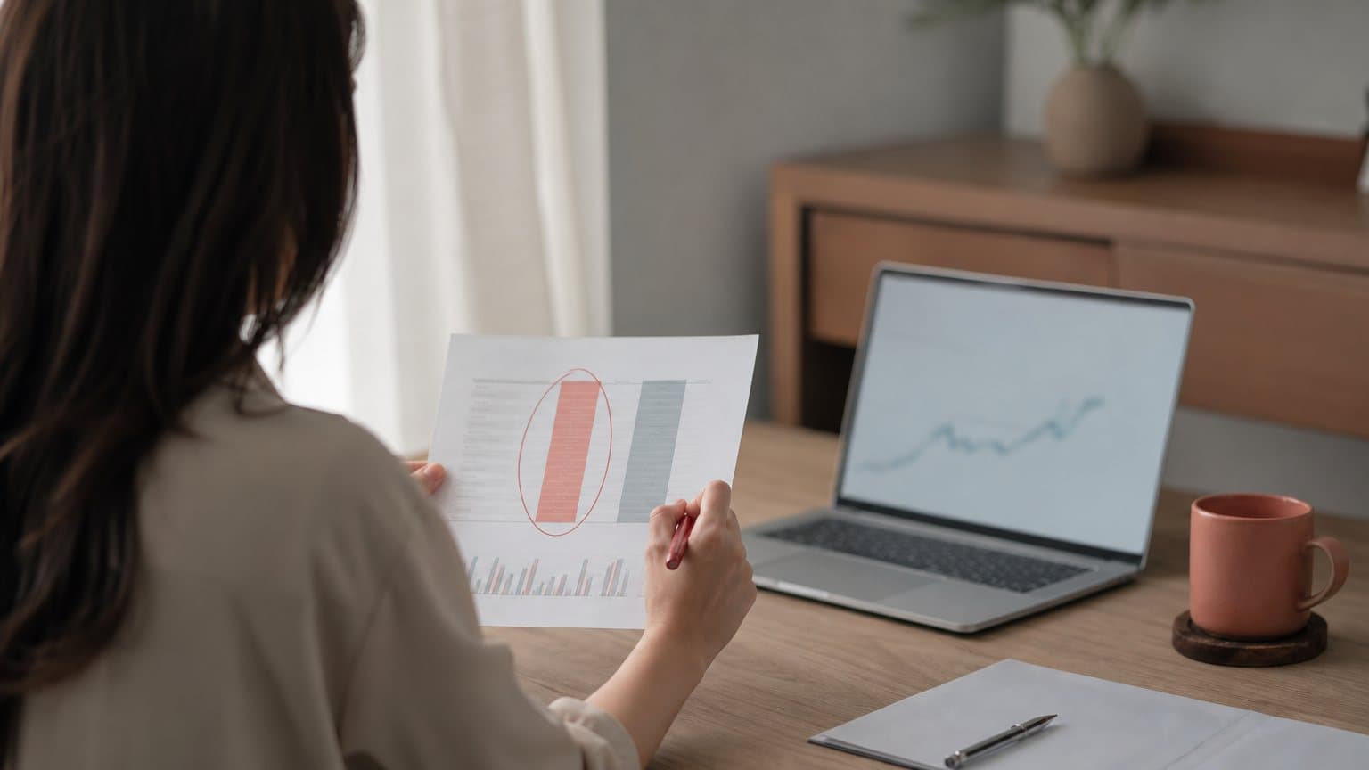 A paid media analyst circling one column of a printed performance report while the column beside it goes unmarked